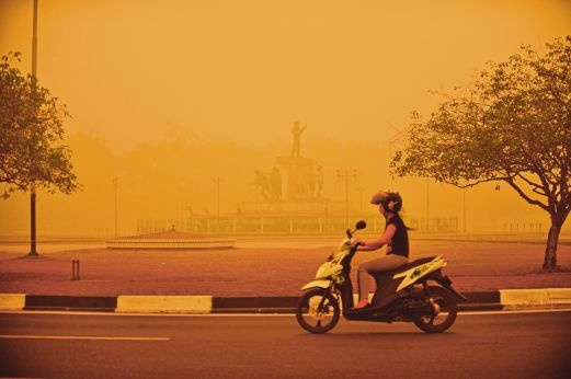 SEORANG wanita menunggang motosikal ketika jerebu tebal berwarna kuning menyelimuti Palangkaraya di Kalimantan Tengah, semalam.