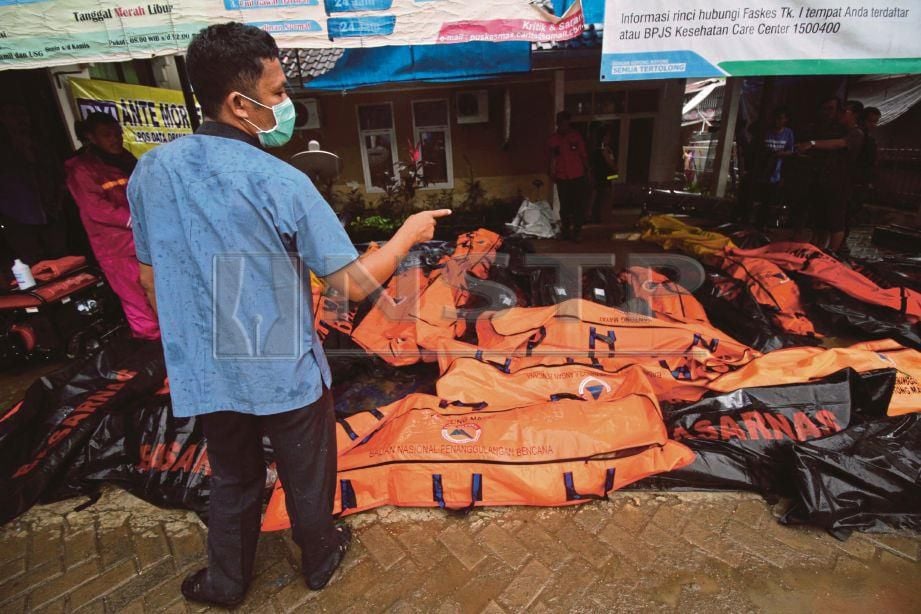 PETUGAS keselamatan mengira bungkusan yang mengandungi mayat mangsa tsunami yang dikumpulkan di rumah mayat Carita, Banten. 