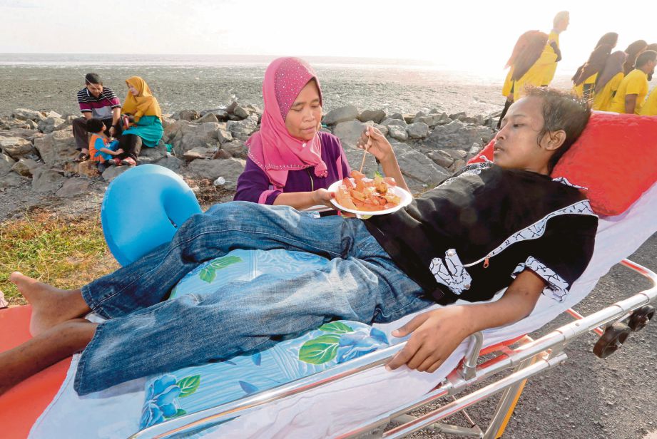 MUHAMAD Nasri menjamah lokcing yang dihulurkan Zaleha di Pantai Kurung Tengar, Kuala Perlis.