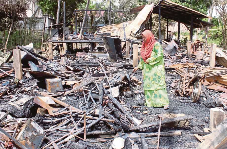 Rozita  mencari saki baki barang yang terselamat  dalam kebakaran di Kampung Dusun Langgar.  