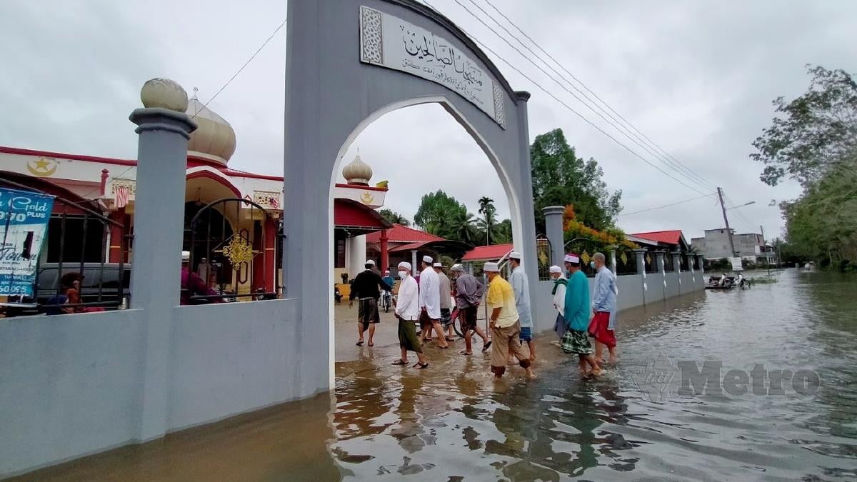 JEMAAH terpaksa meredah limpahan air kira-kira sejauh 200 meter sebelum tiba di Masjid As-Solihin untuk Solat Jumaat. FOTO Nik Abdullah Nik Omar