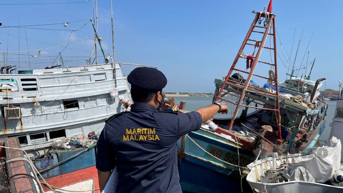 PEGAWAI APMM menunjukkan bot nelayan Vietnam yang ditahan selepas menceroboh perairan negara. FOTO Ghazali Kori