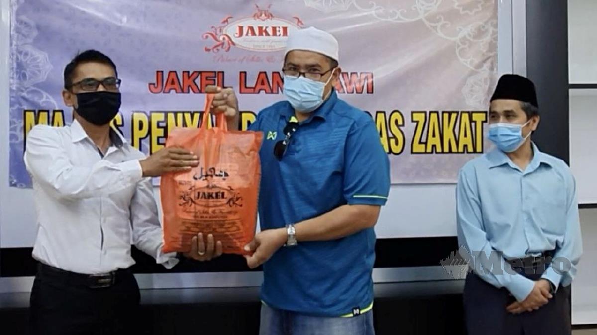 ZULKIFLI (kiri) menyampaikan sumbangan beras kepada wakil jawatankuasa kariah masjid. FOTO Hamzah Osman