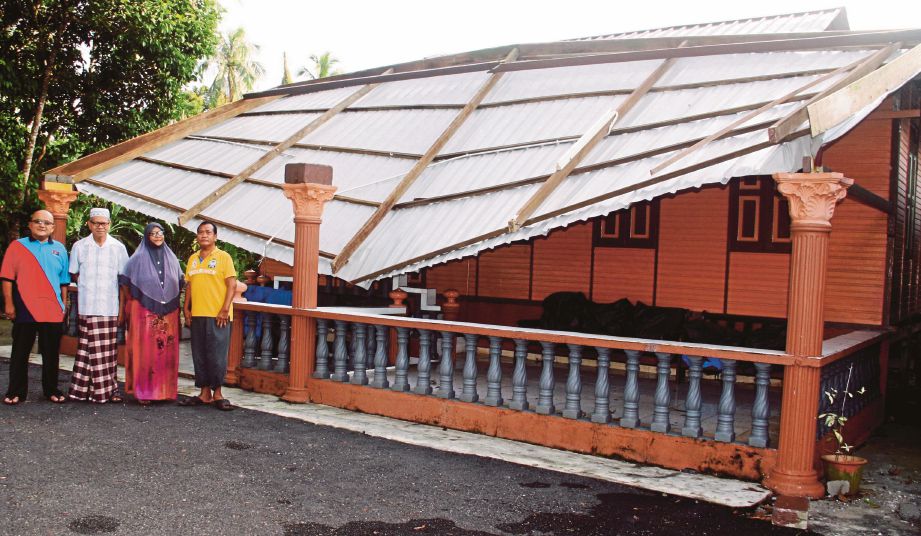 ANUAR  (dua dari kiri) di rumahnya yang  bumbung anjung terbalik akibat dipukul ribut di Kampung Serkat, Kukup Pontian. 