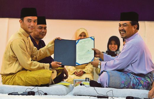  JAMIL  (kanan) menyampaikan sijil nikah sementara kepada pengantin Mohd Amirul Ahmad Fauzi (kiri) dan pasangannya Nur Shuhada Nabila Abdul Razak (tengah) pada Majlis Walimatul 'Urus Perdana Asnaf Baitulmal MAIWP di Masjid Wilayah Persekutuan, semalam.