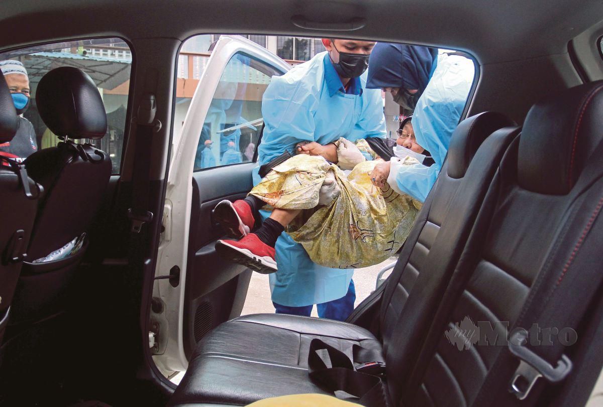 ANGGOTA APM mengangkat seorang warga emas, Jah Rasiah Ab Rahman, 82, ke dalam kereta di hadapan rumahnya untuk mendapatkan suntikan vaksin Covid-19. FOTO Nik Abdullah Nik Omar