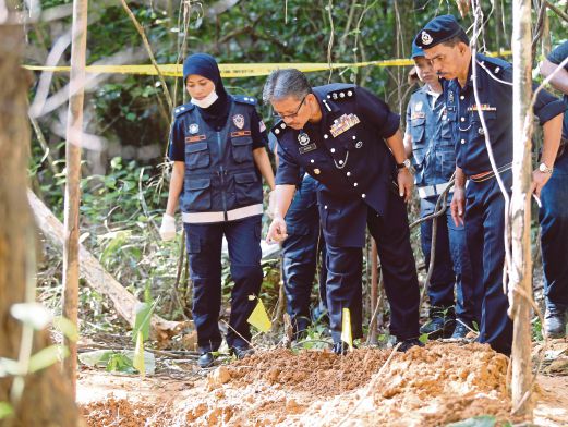 Mohd Nashir (dua dari kiri) melihat mayat yang ditanam dalam lubang di Hutan Simpan Charok. 