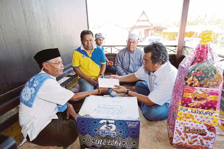 Mustapa  (kanan) menyampaikan sumbangan kepada Ab Rahman  sambil diperhatikan  Othman  (dua dari kiri) dan Md Yaman  (dua dari kanan) pada program lawatan semula Titipan Kasih Harian Metro di Tanjung Dahan, Kuala Sungai Baru.  