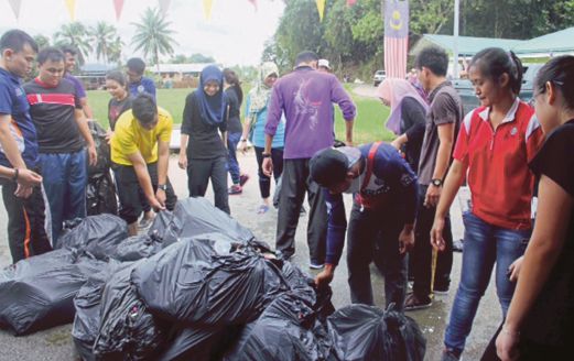 PENUNTUT UiTM bantu angkat sampah di Kampung Endap, semalam.