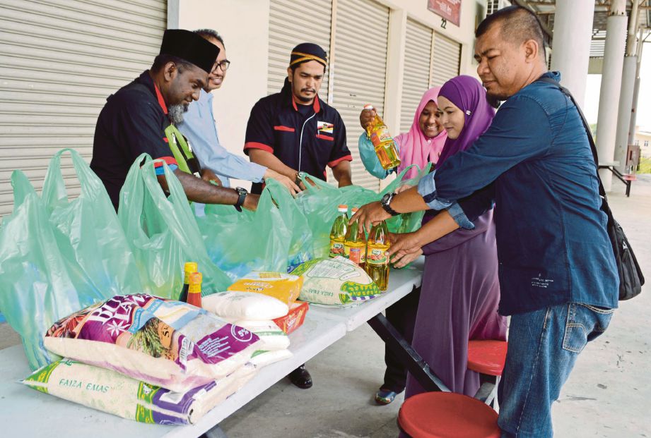 MOHD Shamsul (tiga dari kiri) bersama sukarelawan menyusun barangan keperluan harian hasil sumbangan orang ramai.
