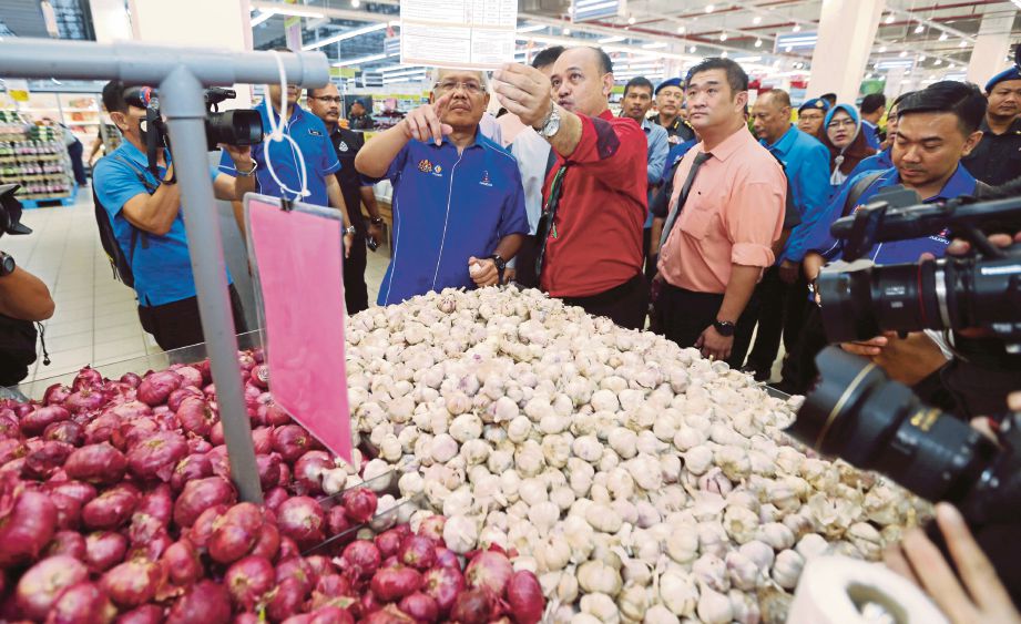 HAMZAH  (tengah) meninjau harga bawang putih yang dijual di sebuah pasar raya.