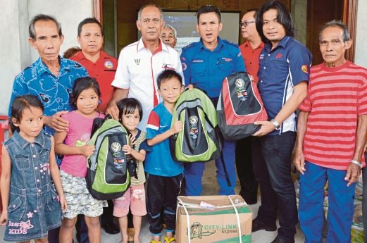  Shamran (dua dari kanan) menyerahkan beg keperluan asas sumbangan  Media Prima kepada mangsa banjir di Kampung Bidayauh Tebakang, Serian.