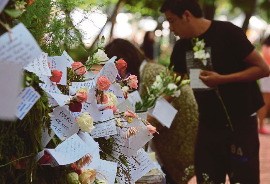 ORANG ramai meletakkan bunga dibina untuk memperingati mangsa di Mexico City. - AFP  