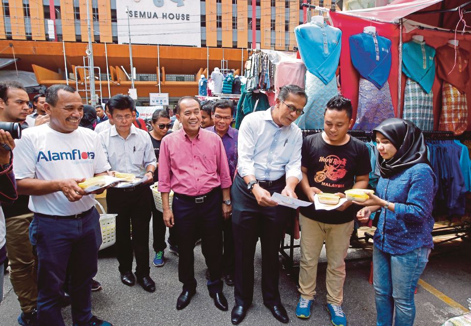  MOHD Zain  (tiga dari kanan) menyerahkan bubur lambuk kepada peniaga sambil diperhatikan Pengarah Eksekutif (Pembangunan Sosioekonomi) DBKL, Datuk Ibrahim Yusoff (lima dari kanan) pada  majlis agihan 1,500 bekas makanan dan bubur lambuk secara percuma di Jalan Bunus 6, Kuala Lumpur, semalam.