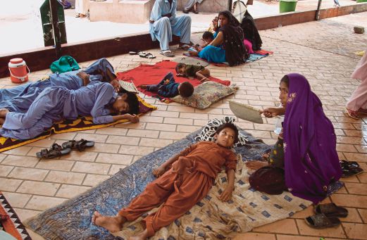 SEORANG wanita mengipas anaknya yang kepanasan ketika menanti giliran untuk mendapat rawatan di sebuah hospital di Karachi, semalam.   