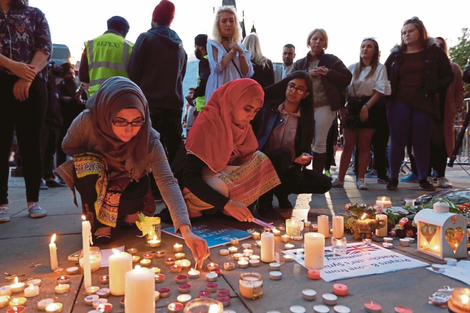 SEKUMPULAN wanita Muslim turut menyalakan lilin di tengah Manchester sebagai mengenang mangsa yang terkorban dalam serangan kejam kelmarin.  - Reuters 