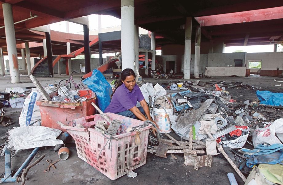 Aizalina Ahmad memeriksa barangan lusuh yang dikutip berhampiran sebuah syarikat pembinaan di Jalan Labohan Dagang-Nilai. 