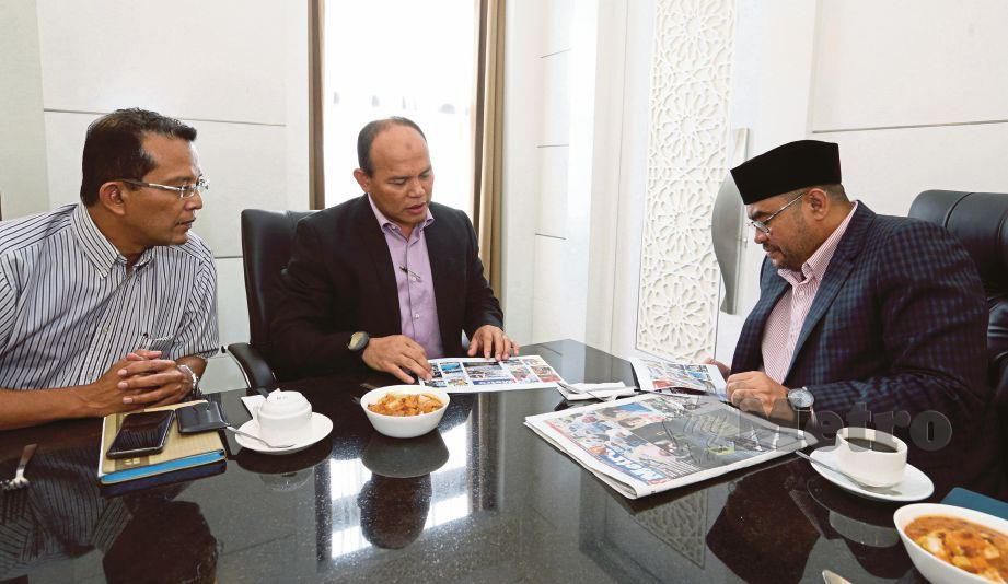 MUJAHID  melihat akhbar Harian Metro bersama  Husain  (tengah) dan  Ahmad Shahrul  semasa kunjungan hormat di Kompleks Islam Putrajaya. 