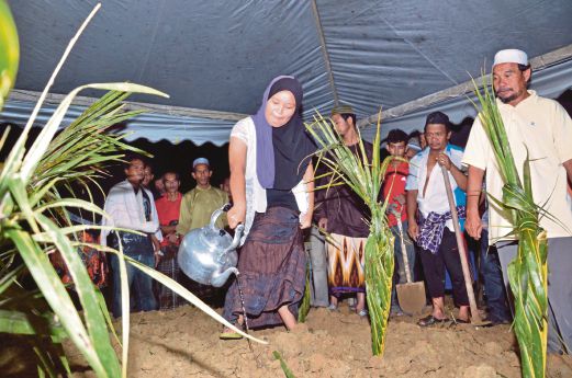 Nor Ain Syakira   sebak ketika menyiram air ke pusara dua anak kembarnya di Tanah Perkuburan Islam Kampung Panggung Lalat, Gua Musang. 