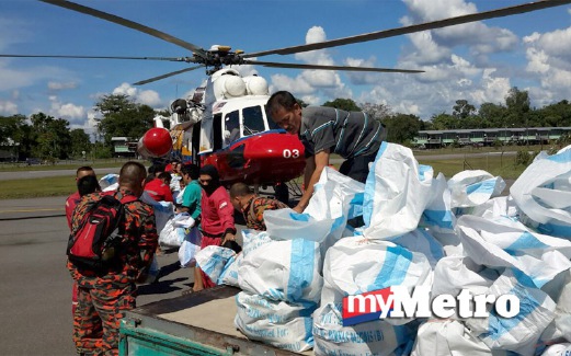 PENDUDUK membantu memindahkan bantuan makanan ke dalam helikopter di Lapangan Terbang Marudi. FOTO Mohd Rizal Abdullah