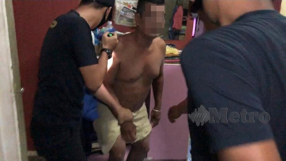 ANGGOTA polis menahan lelaki dipercayai tokan dadah yang menyorok dalam almari baju ketika serbuan. FOTO Zuliaty Zulkiffli