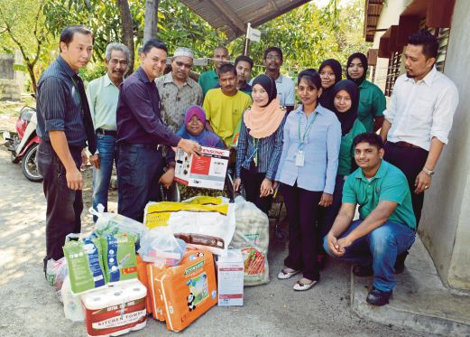 Zamzuri (tiga dari kiri) menyampaikan sumbangan barangan keperluan harian kepada Siti Aminah (berkerusi roda) di rumah mereka di Bagan Dalam, semalam.
