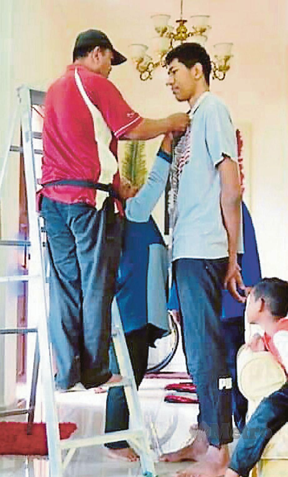 TUKANG jahit terpaksa menggunakan tangga untuk mengambil ukuran baju Mohd Azli Hisyam.