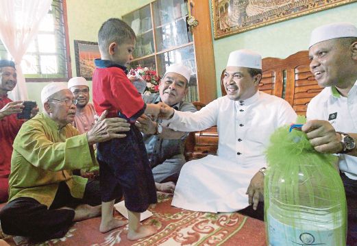 JAMIL Khir (dua kanan) bertanya khabar kepada anak tunggal waris mangsa kren runtuh di Mekah, Muhammad Afiq.