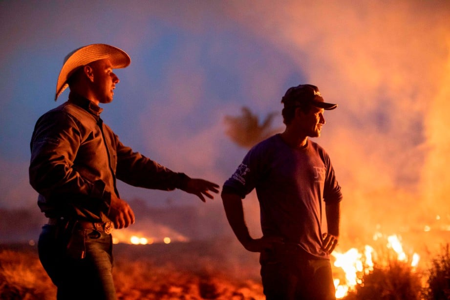 DUA buruh memerhatikan kebakaran hutan yang merebak ke ladang mereka di Mato Grosso, selatan Amazon. FOTO AFP