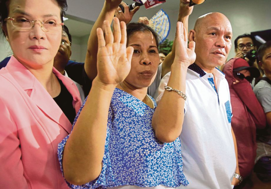 PERSIDA (kiri) mengiring ibu bapa pelajar terbabit, Saldy (tengah) dan Lorenza Delos Santos (kanan) mengangkat sumpah ketika memfailkan tuduhan bunuh terhadap tiga polis berkenaan. - Reuters 