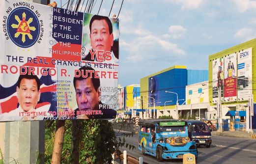 SEBUAH jeepney melintas di hadapan poster pilihan raya Duterte di Davao, semalam. 