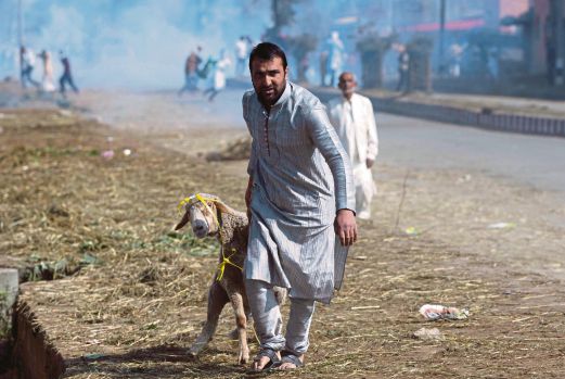 SEORANG lelaki Kashmir lari membawa kambing belaannya ketika penunjuk perasaan merusuh selepas solat Aidiladha di Srinagar.