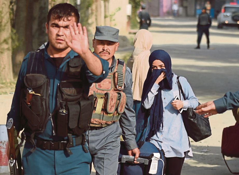 POLIS mengiringi pelajar perempuan yang terperangkap di dalam kampus. - AFP