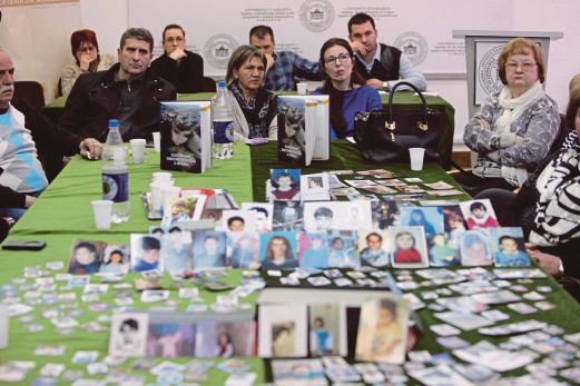GAMBAR mangsa keganasan Serb dipamerkan di atas meja ketika sekumpulan penduduk Islam Bosnia di Sarajevo menonton siaran langsung keputusan perbicaraan  Karadzic di The Hague, kelmarin.  