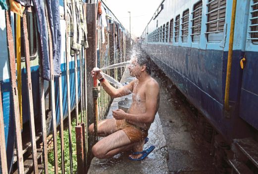 SEORANG penumpang mandi di landasan kereta api di Jammu ketika cuaca panas turut melanda wilayah berkenaan, semalam. 