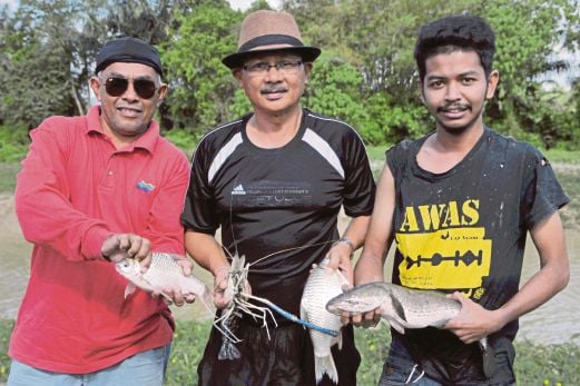 MOHD Hazry Abd Rahman (kanan) bersama ikan yang berjaya ditangkap ketika mengoca di Empang Bangkung, Juasseh. 