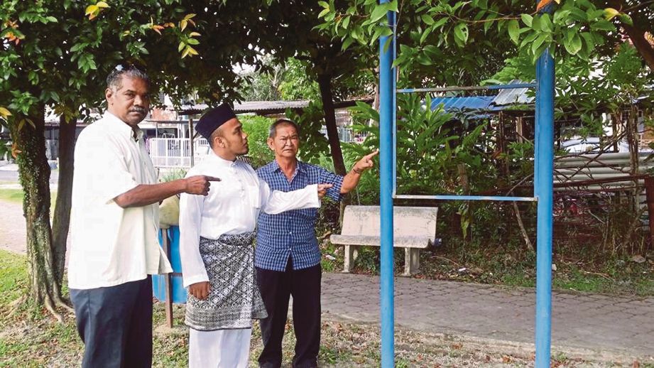 MOHD Firdaus (tengah) menunjukkan papan tanda yang hilang.