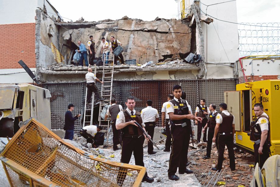 POLIS dan pengawal memeriksa bilik kebal yang diletupkan dan turut memusnahkan bangunan Prosegur di Ciudad del Este, Paraguay. - AP 