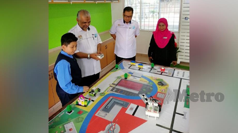 MURID menunjukkan cara mengawal kenderaan robotik ketika perasmian bilik khas DELIMa kepada Shafruddin Ali (dua kiri). FOTO ihsan SSTP