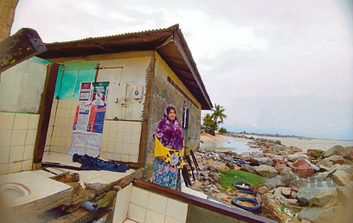ZAINAB menunjukkan bahagian bilik air dan tandas yang runtuh akibat hakisan serta ombak kuat dalam kejadian awal pagi Khamis lalu  di Kampung Pengkalan Atap, Kuala Besut, Terengganu. - FOTO NURUL FATIHAH SULAINI