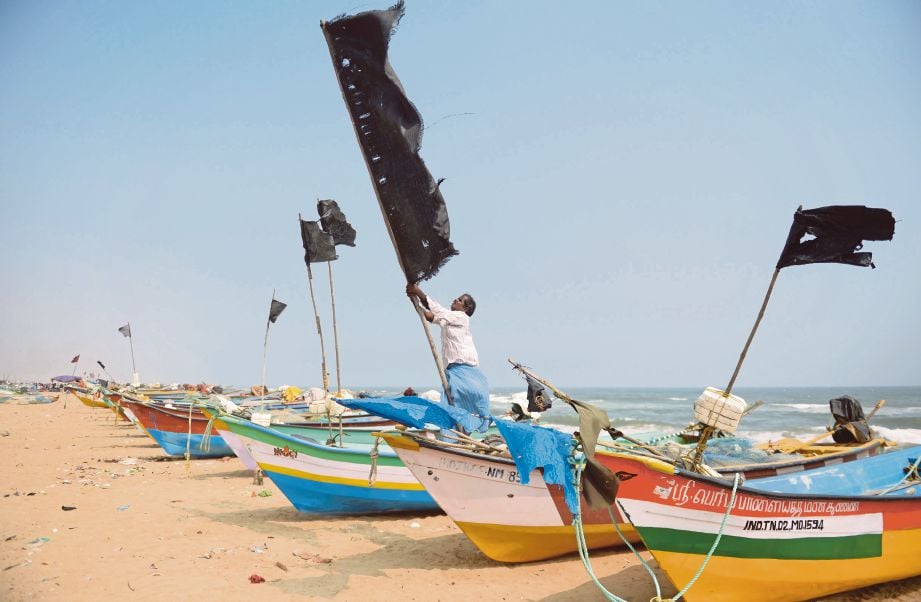 Seorang nelayan memasang bendera hitam di bot  semasa upacara peringatan bagi mangsa tsunami tahun 2004 di Pantai Pattinapakkam di Chennai, India.
