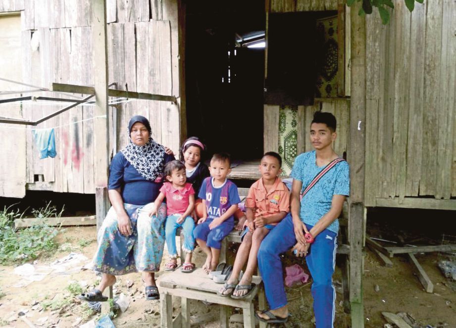 AZIZAH (kiri) bersama lima anaknya di hadapan rumah usang mereka.