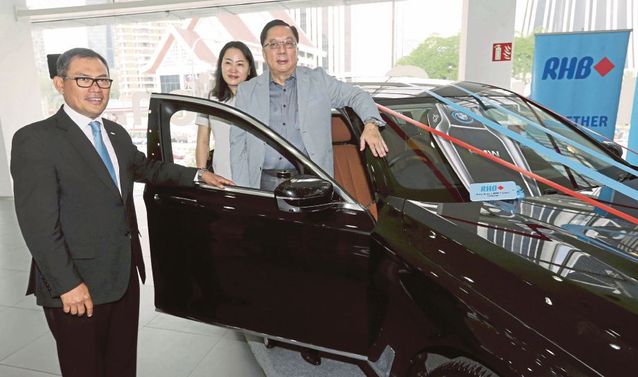 NAZRI (kiri) menyerahkan hadiah utama kempen Drive Home A BMW Series kepada Tan (kanan) dan isterinya.