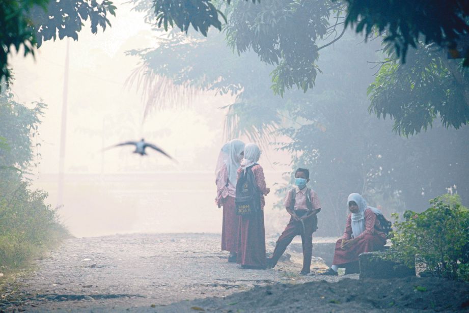PELAJAR di Meulaboh di Aceh memakai topeng kerana asap tebal yang melanda daerah itu. - AFP
