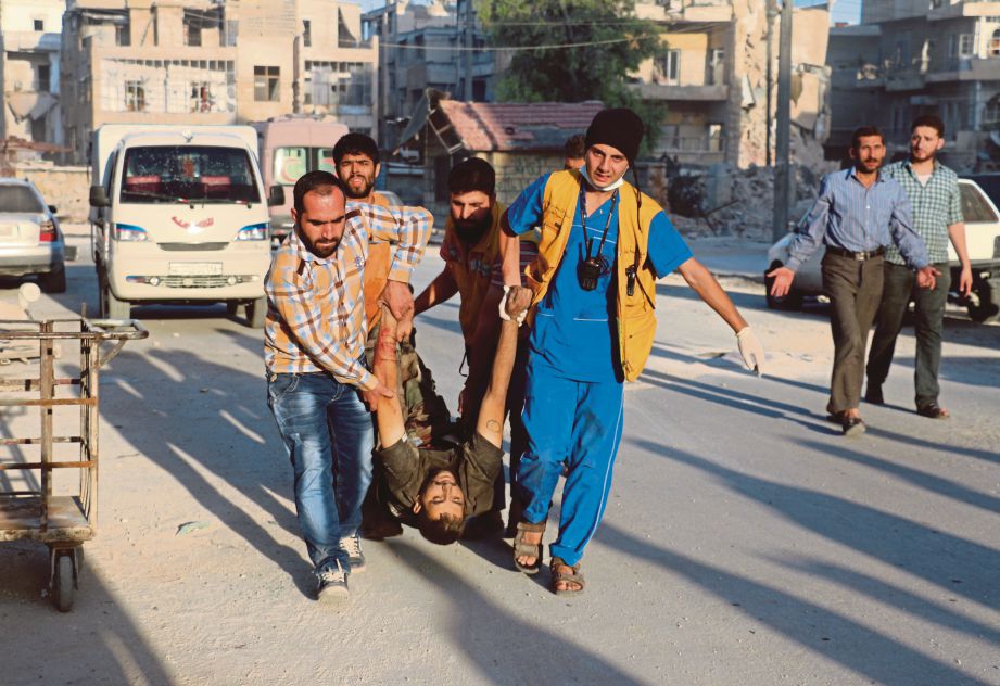 SEKUMPULAN sukarelawan Russia dengan dibantu penduduk mengangkat mangsa serangan udara di daerah Salaheddin, Aleppo, semalam. - AFP 