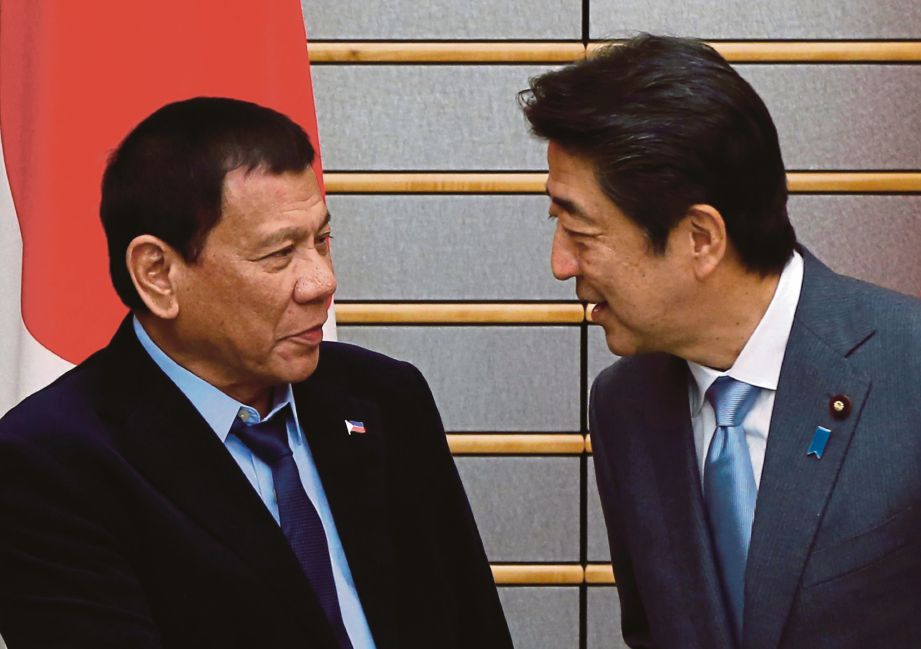 DUTERTE (kiri) disambut oleh Perdana Menteri Jepun, Shinzo Abe sebelum mereka memulakan mesyuarat di kediaman rasmi Abe, di Tokyo, semalam.  - AP