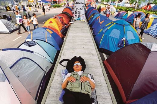 SEORANG lelaki tidur antara khemah yang didirikan aktivis prodemokrasi di tengah Hong Kong, semalam. 