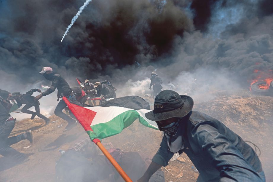 PENUNJUK perasaan Palestin lari untuk berlindung daripada terkena  gas pemedih mata Israel ketika protes. FOTO Reuters (Fail)