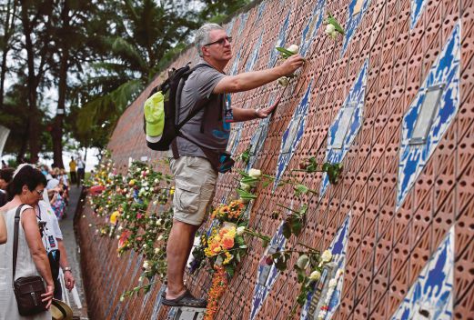 SEORANG lelaki Jerman meletakkan bunga pada tembok tugu mangsa tsunami di Dataran Tsunami di Baan Nam Khem, wilayah Phanga di selatan Thai.  