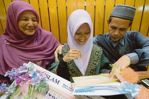 Wan Nurul Husna  menunjukkan anugerah yang diperoleh kepada ibu bapanya, Wan Shukri dan Nisah  selepas Majlis Graduasi Tahfiz Yayasan Islam Kelantan di Balai Islam. 